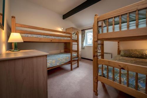 a bedroom with two bunk beds and a desk at Rose Cottage in Llanbedrog