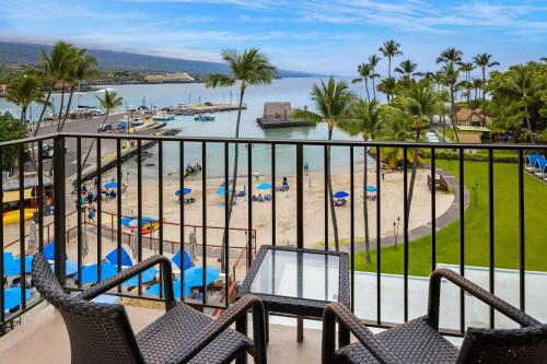 a balcony with chairs and a beach with palm trees at Courtyard by Marriott King Kamehameha's Kona Beach Hotel in Kailua-Kona