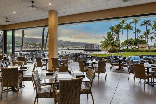 a restaurant with tables and chairs and a view of the ocean at Courtyard by Marriott King Kamehameha's Kona Beach Hotel in Kailua-Kona