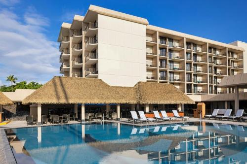 a resort with a swimming pool with chairs and a building at Courtyard by Marriott King Kamehameha's Kona Beach Hotel in Kailua-Kona