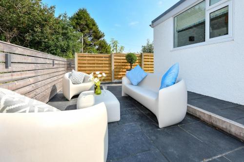 a patio with two white chairs and blue pillows at Hillview in Llanbedrog
