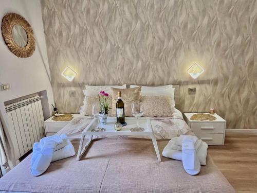 a white bed with a table with a bottle of wine at Mazzocchi House welcome wine in Naples
