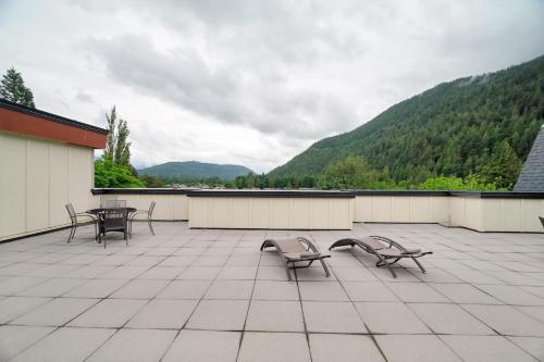 a patio with chairs and tables with mountains in the background at 1BR Lakeside Getaway on Harrison Lake in Harrison Hot Springs