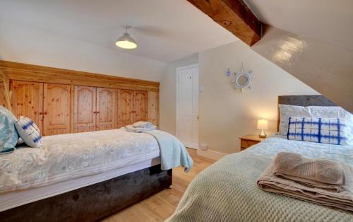 Dos camas en un dormitorio con paredes de madera. en Clifton House, en Lynmouth