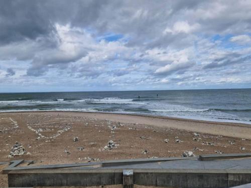 a beach with surfers in the ocean on a cloudy day at 6 person holiday home in Thisted-By Traum in Torsted