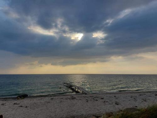 a beach with a cloudy sky and the ocean at 4 person holiday home in Store Fuglede-By Traum in Store Fuglede