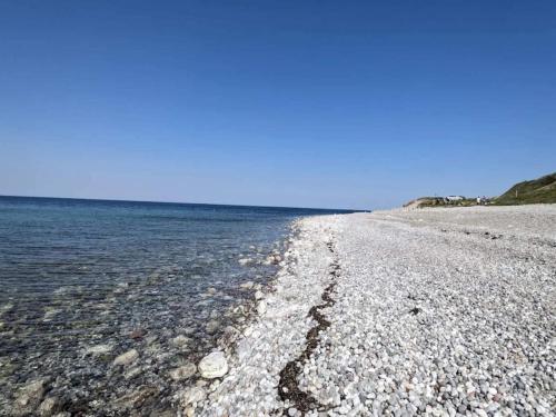 a beach with rocks and water on a clear day at 6 person holiday home in Nykøbing Sj-By Traum in Klint