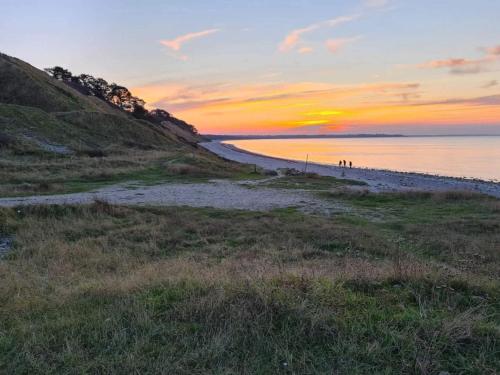 a beach at sunset with people walking on it at 6 person holiday home in Nykøbing Sj-By Traum in Klint