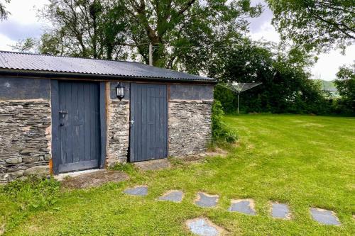 a stone building with a blue door in a field at Pwllglas in Darowen
