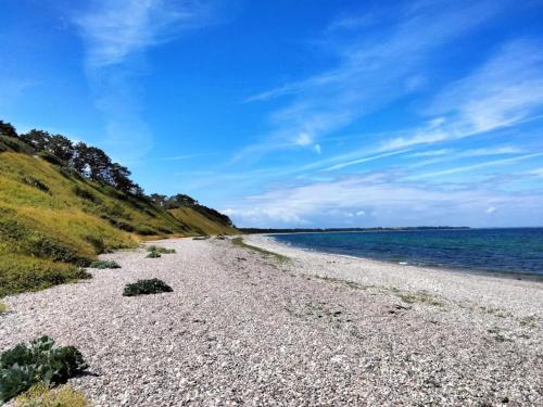 a rocky beach next to the ocean on a sunny day at 6 person holiday home in Nykøbing Sj-By Traum in Klint