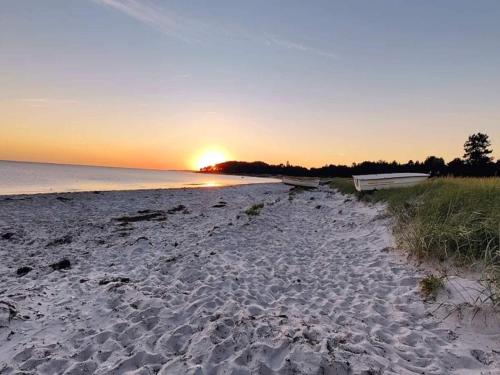 a sandy beach with the sun setting over the water at 6 person holiday home in Nykøbing Sj-By Traum in Klint