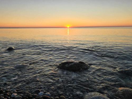 a sunset over the ocean with rocks in the water at 6 person holiday home in Nykøbing Sj-By Traum in Klint