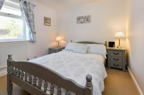 a bedroom with a bed and two night stands and a window at 243 Cae Du in Abersoch