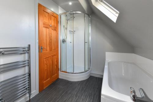 a bathroom with a shower and a sink and a wooden door at 243 Cae Du in Abersoch