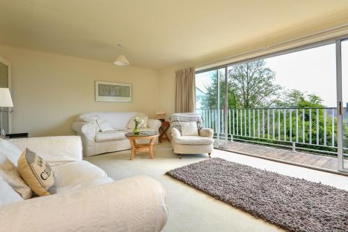 a living room with a couch and chairs and a balcony at Gerddi in Llanbedrog