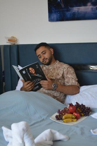 a man laying in bed reading a book with a plate of food at king pyramids in Cairo