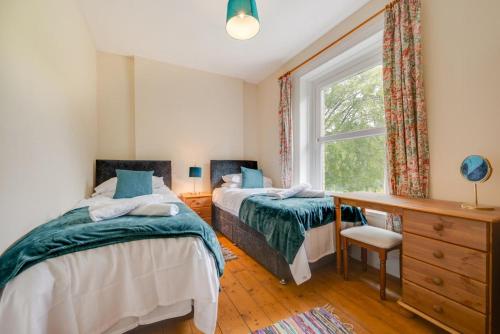 a bedroom with two beds and a window at Greengrove Farmhouse Glasallt in Llangadog