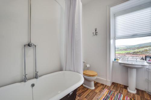 a white bathroom with a tub and a sink at 1 Rose Cottage in Hawes