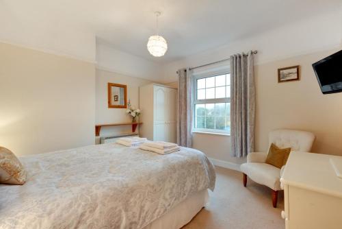 a bedroom with a bed and a chair and a window at Coastguard Cottage in Blagberry
