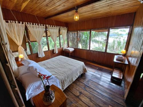 a bedroom with a bed in a room with windows at Andean Wings Sotupa Eco Lodge in Puerto Maldonado
