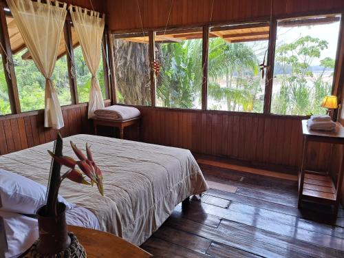 a bedroom with a bed and a table and windows at Andean Wings Sotupa Eco Lodge in Puerto Maldonado