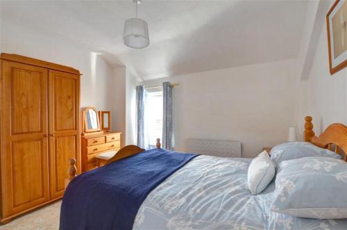 a bedroom with a bed and a wooden cabinet at Glandon in Aberdaron