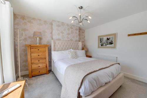 - une chambre avec un lit, une commode et une lampe dans l'établissement Sandpiper Cottage, à Saundersfoot