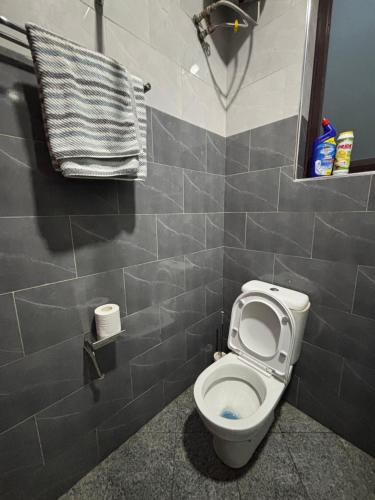 a bathroom with a toilet and a tiled wall at Kampala Kyanja Expatriate Living in Kampala