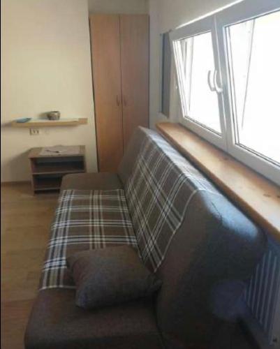 a couch sitting in a living room with a window at 3 kambariu butas in Klaipėda