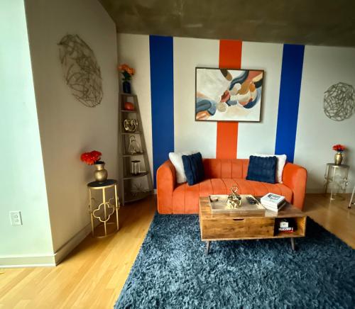 a living room with an orange couch and a table at Luxury Midtown High-rise Oasis! in Atlanta