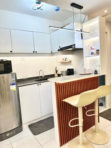 a kitchen with white cabinets and a bar with a stool at 2 Bedroom Elegant Condo Cebu in Mandaue City