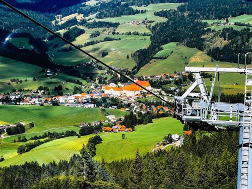 a gondola flying over a green valley with a town at Grebenzen Top Chalet Mazzel in Sankt Lambrecht