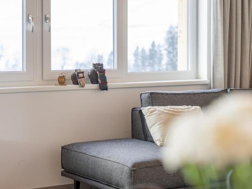 a gray chair sitting in a room with windows at Grebenzen Top Chalet Mazzel in Sankt Lambrecht