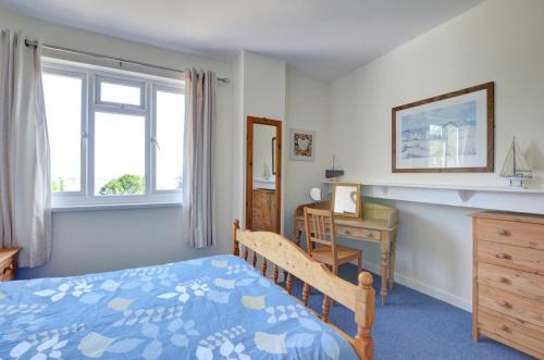 a bedroom with a bed and a desk and window at Elvor in New Quay