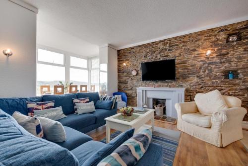 a living room with a blue couch and a stone wall at The Gulls in Looe