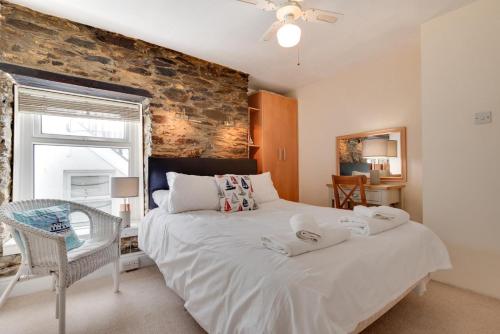 a bedroom with a large white bed and a brick wall at The Gulls in Looe