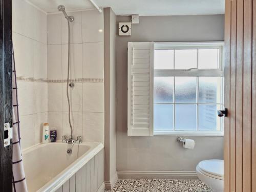 bagno con vasca, servizi igienici e finestra di Unique & Stylish Town House in Central Cheltenham a Cheltenham