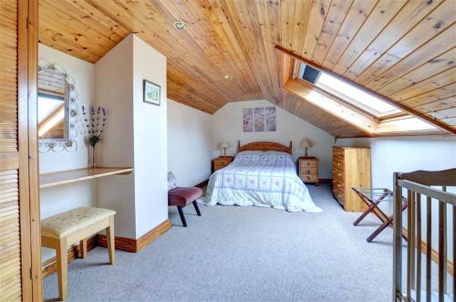 a bedroom with a bed and a wooden ceiling at Tyn Coed in Moelfre