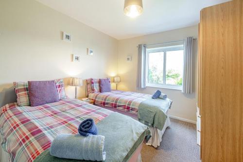 a bedroom with two beds and a window at Llwyn y Morfa in Morfa Nefyn