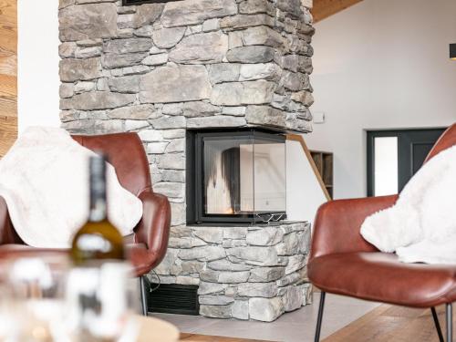 a living room with two chairs and a stone fireplace at Grebenzen Lodge 35 in Sankt Lambrecht