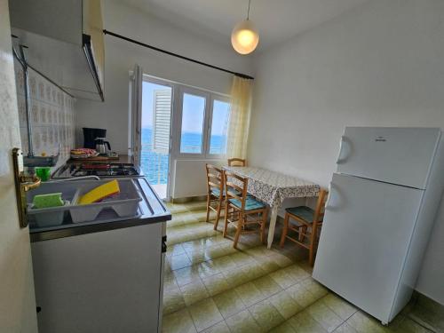 a kitchen with a white refrigerator and a table with chairs at Apartments by the sea Savar, Dugi otok - 8079 in Brbinj
