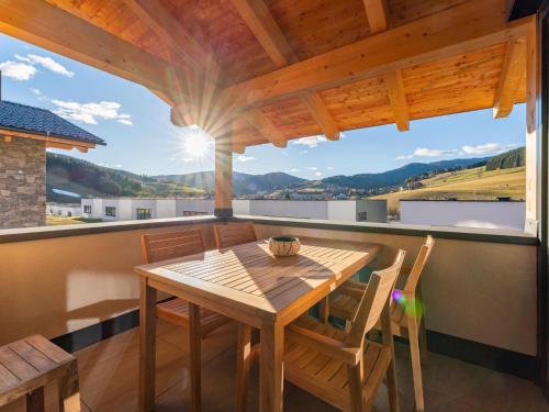 a wooden table and chairs on a balcony with a view at Grebenzen Eiszeit Lodge in Sankt Lambrecht
