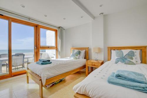 two beds in a room with a view of the ocean at Ocean Blue in Porthleven