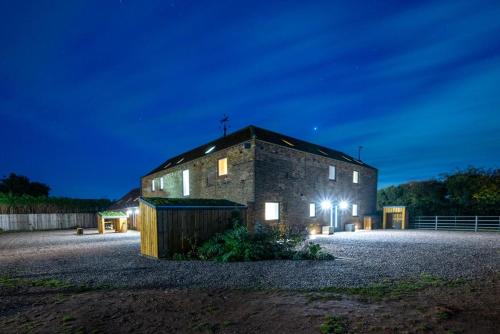 an old stone building with a cross on top at night at The Barn at The Foldyard in Holme upon Spalding Moor