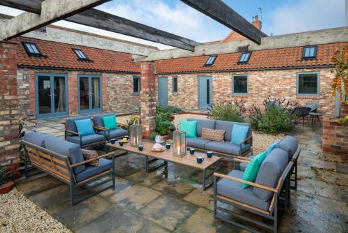 a patio with blue chairs and a wooden table at The Barn at The Foldyard in Holme upon Spalding Moor