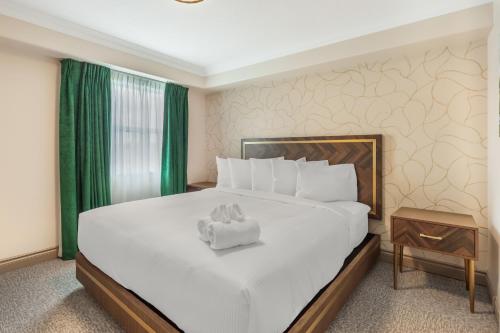 a bedroom with a large white bed with green curtains at Velora Hinton, an Ascend Collection Hotel in Hinton