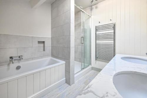 a white bathroom with a tub and a sink at Tyr Ysgol in Pwllheli