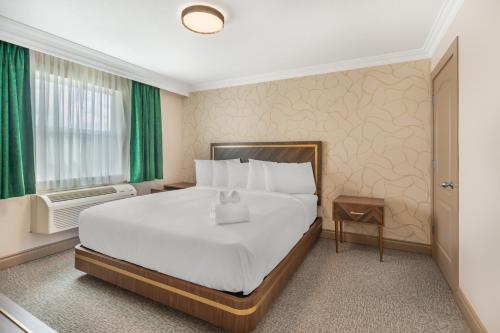 a hotel room with a large bed and green curtains at Velora Hinton, an Ascend Collection Hotel in Hinton