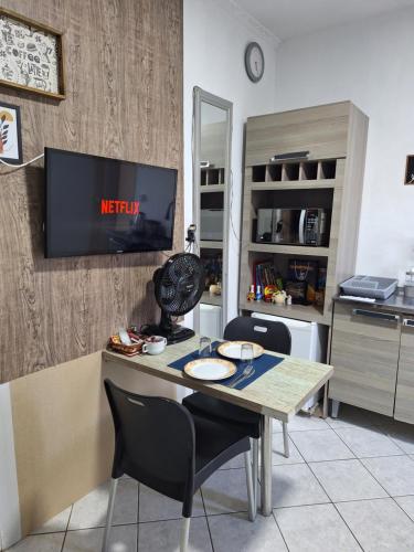 a kitchen with a table and a tv on a wall at Studio Nerd em Floripa in Florianópolis