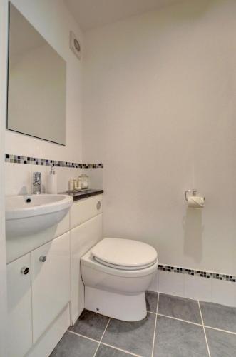a white bathroom with a toilet and a sink at Mariners in Barbrook